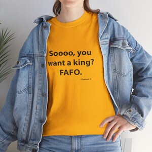 Op de afbeelding: Mosterdgeel T-shirt met de tekst "Soooo, you want a king? FAFO." in het zwart. De tekst "-1 Samuel 8" staat eronder. De persoon draagt een spijkerjasje.