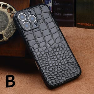 May include: Black phone case with a crocodile skin texture. The case has a glossy finish and features three camera lenses. The letter "B" is visible in the lower left corner.