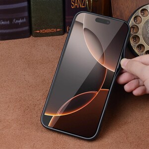 May include: A black smartphone with a screen displaying an abstract design in shades of brown and orange. The phone is held by a hand, showcasing its sleek design. The phone case is black.