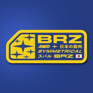 May include: A yellow and blue sticker with the text "BRZ" in large, bold letters. The sticker also includes the words "AWD", "SYMMETRICAL", and Japanese text. The design features star-like shapes and a Japanese flag.