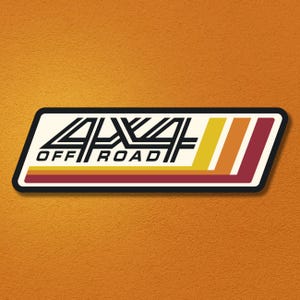 May include: A rectangular decal with a cream background featuring the black text 4x4 OFF ROAD. The design includes three diagonal stripes in yellow, orange, and dark red on the right side, all enclosed within a thick black border.