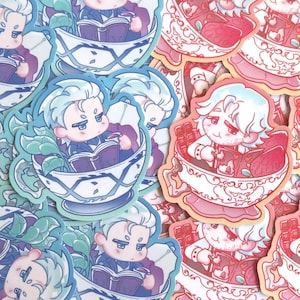 May include: A selection of stickers depicting cartoon characters in teacups. One sticker shows a character reading a book in a blue and white teacup. Another shows a character with chocolate and strawberries in a pink teacup. The stickers have a cute, whimsical style.