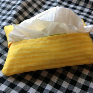 May include: A yellow and white striped fabric tissue box cover with a white tissue inside.