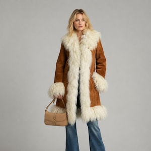 May include: A tan suede coat featuring long, shaggy white faux fur trim along the front opening, collar, and cuffs. The coat is paired with blue denim flare jeans and a tan leather shoulder bag with a gold-tone buckle detail on the front.