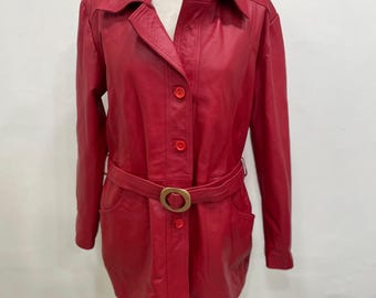 May include: A red leather jacket with a collared neckline, button closures, and a matching belt with a gold-tone buckle. The jacket has long sleeves and two front pockets. The jacket is displayed on a mannequin.