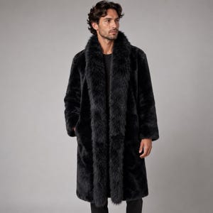 May include: A long, black faux fur coat featuring a thick, plush shawl collar that extends down the front. The coat has long sleeves and a straight, knee-length silhouette, providing a full-coverage design with a dense, textured appearance.