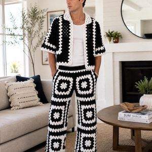 May include: A black and white crochet matching set consisting of a short-sleeved button-down shirt with a collar and wide-leg trousers. The garment features a repeating granny square pattern throughout, layered over a plain white tank top.