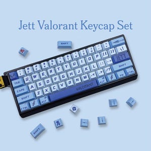 May include: A blue and black mechanical keyboard with light blue keycaps. The keycaps have white lettering and symbols. The keyboard has the text "Jett Valorant Keycap Set" above it. Several loose keycaps are scattered around the keyboard.