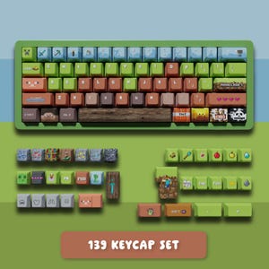 May include: A green and blue keyboard with custom keycaps. The keycaps feature pixelated designs and icons, including TNT, Minecraft, and other game-related graphics. The text "139 KEYCAP SET" is displayed below the keyboard.