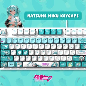 Puede incluir: Teclado blanco con teclas personalizadas con ilustraciones de Hatsune Miku. Las teclas son blancas y turquesas, con ilustraciones del personaje. El teclado tiene el texto "HATSUNE MIKU KEYCAPS" y texto japonés.