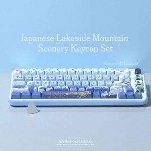 May include: A mechanical keyboard with a Japanese lakeside mountain scenery keycap set. The keycaps feature a gradient of blue and white colors, with landscape designs. The keyboard is on a light blue surface. The text "Japanese Lakeside Mountain Scenery Keycap Set" is visible.