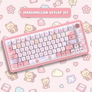 以下が含まれることがあります： 「Marshmellow Keycap Set」デザインのピンクと白のキーボード。キーボードは、クマとキャンディのイラストで飾られたカスタムキーキャップを備えたQWERTYレイアウトです。キーは白でピンクと青のアクセントがあり、フレームはピンクです。