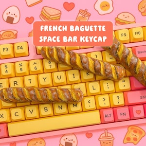 Può includere: Una tastiera rosa e gialla con un keycap a barra spaziatrice a forma di baguette francese. La tastiera ha tasti gialli con lettere bianche. L'immagine presenta anche illustrazioni a tema cibo, tra cui panini e pizza.