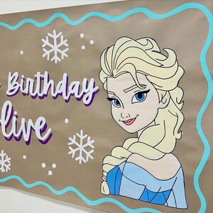 May include: A brown banner featuring a cartoon illustration of a blonde woman with blue eyes and a blue dress. The banner has the words "Birthday Live" in white and purple lettering, along with white snowflakes and a blue border. The banner is likely for a birthday party.