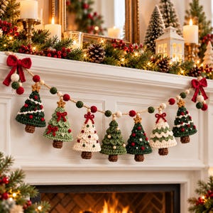 Op de afbeelding: Een feestelijke slinger met zeven gehaakte kerstbomen in tinten donkergroen, lichtgroen en crème, versierd met kleine rode strikjes, sterretjes en kralen. De bomen zijn geregen aan een dik jute touw met afwisselend rode en groene vilten balletjes.