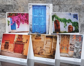 May include: A collection of six folded greeting cards featuring photographs of doors and architectural details. The images showcase colorful doors, buildings, and a bicycle, with the word "MAMA" printed on the bottom of each card.