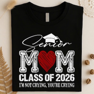 May include: Black t-shirt with white text and a red heart. The shirt says "Senior Mom" with a graduation cap graphic, "Class of 2026," and "I'm not crying, you're crying."