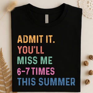 Op de afbeelding: Zwart T-shirt met de tekst "ADMIT IT. YOU'LL MISS ME 6-7 TIMES THIS SUMMER" in oranje, roze, groen en blauw. Het shirt heeft een ronde hals.