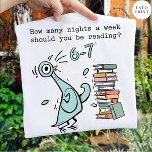 K&ouml;nnte beinhalten: Wei&szlig;e Tragetasche mit einem Cartoon-Tauben-Design und dem Text "Wie viele N&auml;chte pro Woche solltest du lesen?" mit der Antwort "6-7". Ein Stapel B&uuml;cher in verschiedenen Farben ist ebenfalls abgebildet. Die Tasche wird von einer Hand gehalten.