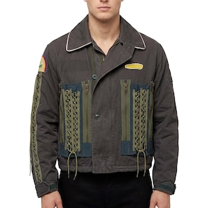 Könnte beinhalten: Dunkelgraue Jacke mit weißem Kragen, olivgrünen und marineblauen Akzenten. Die Jacke hat dekorative Schnürdetails, einen kleinen gelben Aufnäher und einen farbenfrohen Aufnäher am linken Ärmel. Sie hat einen Knopfverschluss und mehrere Taschen.