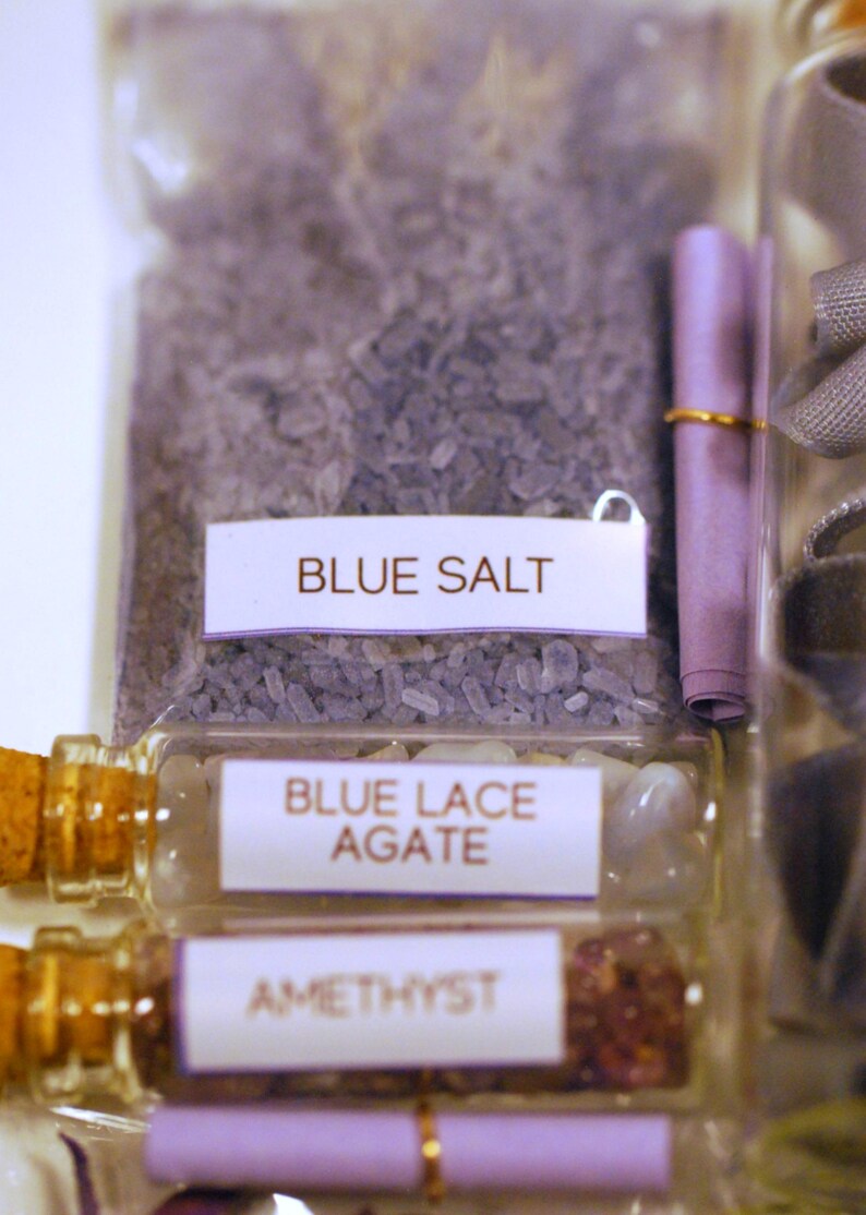 May include: Close-up of various small glass bottles and a clear plastic bag filled with crystals and stones. The bottles contain Blue Lace Agate and Amethyst. The bag is labeled "BLUE SALT".
