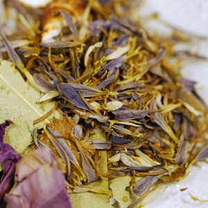 May include: Close-up of dried floral elements, including purple petals, tan stamens, and green leaves. The composition is a mix of textures and colors, with a focus on natural, organic materials. The image suggests a botanical theme.