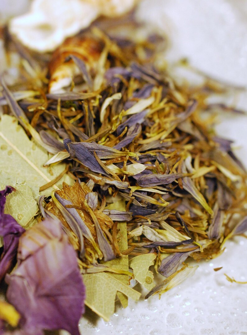 May include: Close-up of dried floral elements, including purple petals, tan stamens, and green leaves. The composition is a mix of textures and colors, with a focus on natural, organic materials. The image suggests a botanical theme.