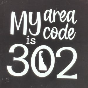 May include: Black sign with white text that reads "My area code is 302". The number 302 includes a white outline of the state of Delaware.