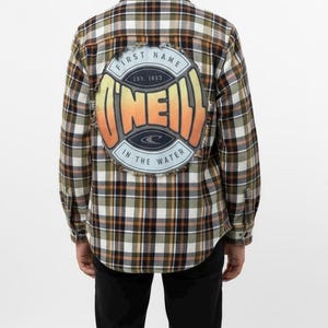 May include: A long-sleeved, button-down flannel shirt with a plaid pattern in shades of brown, green, and white. The back of the shirt features a circular patch with the text "O'Neill" and "First Name In The Water" in a retro design.