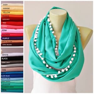 May include: A turquoise infinity scarf with a white pom-pom trim. The scarf is made of a soft, lightweight fabric and is perfect for adding a touch of color to any outfit.
