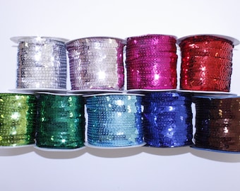 May include: Eight spools of sequined trim in various colors, including silver, pink, red, green, blue, and brown. The trim is wound around white cardboard spools.