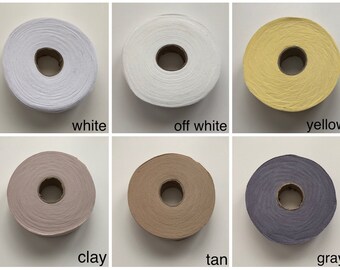 May include: Six spools of yarn in different colors: white, off-white, yellow, clay, tan, and gray.