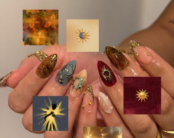 May include: Almond-shaped fingernails featuring intricate 3D nail art designs. The nails display a variety of colors including deep red, brown, and grey, accented with gold metallic sun and moon motifs, swirling patterns, and small embedded gems.
