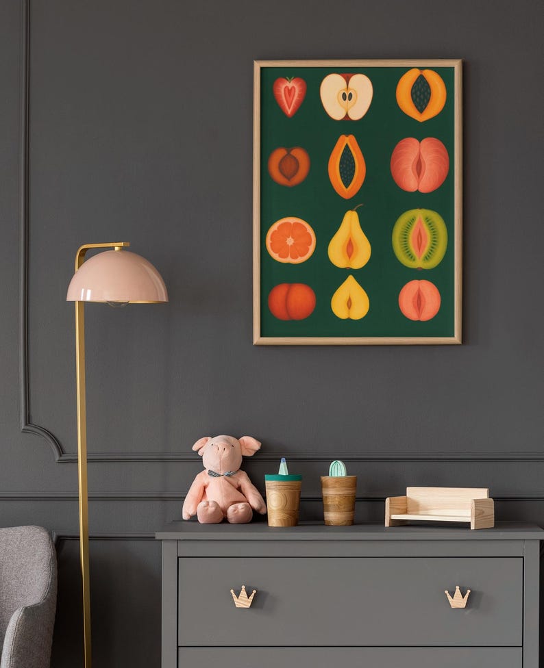 Peut inclure: Une affiche encadr&eacute;e pr&eacute;sentant des illustrations color&eacute;es de divers fruits, dont une fraise, une pomme et un kiwi, sur un fond vert fonc&eacute;. L'affiche est au-dessus d'une commode grise avec des poign&eacute;es en forme de couronne en bois. Un cochon en peluche rose et des tasses en bois sont sur la commode.