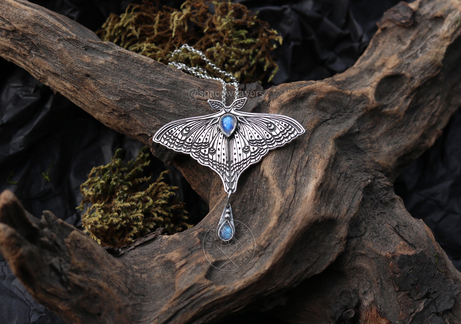 Sterling silver luna moth moonstone necklace, styled on dark driftwood with moss.