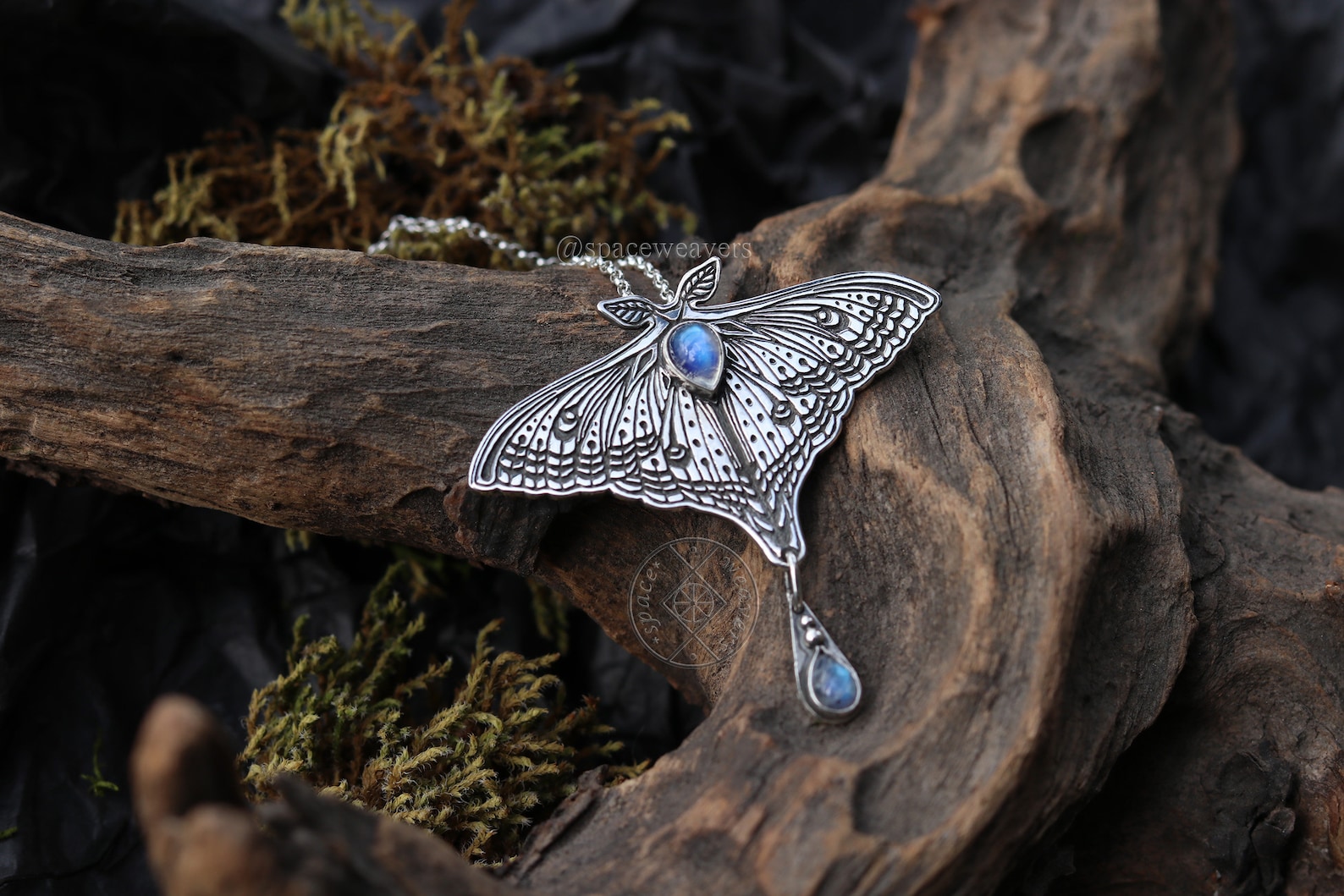 Sterling silver luna moth moonstone necklace, styled on dark driftwood with moss.