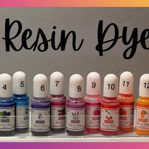 May include: Fifteen small bottles of resin dye arranged in a clear plastic tray. Each bottle features a white cap, a numbered label from 1 to 15, and a colorful graphic representing the pigment shade. The text Resin Dye is printed above.