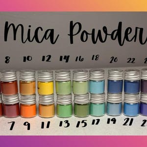 May include: A collection of small, clear glass jars filled with various colors of mica powder, arranged in two rows. Each jar has a silver screw-top lid. The text "Mica Powder" is centered above the jars, with numbers 1 through 30 labeled.