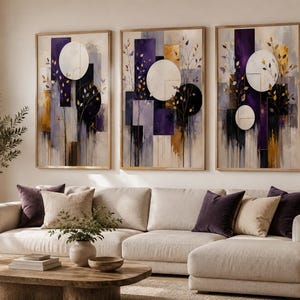Può includere: Un set di tre stampe artistiche da parete verticali incorniciate con forme geometriche astratte, tra cui grandi cerchi bianchi e neri, blocchi rettangolari viola scuro e oro, e delicati motivi a ramo dorato su sfondo neutro.