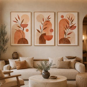 Peut inclure: Un ensemble de trois cadres muraux présentant des formes géométriques abstraites et des illustrations de feuilles botaniques dans des tons terre cuite, orange brûlé et crème. Chaque impression verticale affiche un design cohérent.
