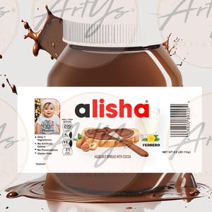 以下が含まれることがあります： 「alisha」とラベルされた、ココア入りヘーゼルナッツスプレッドの瓶。ラベルには赤ちゃんの写真、栄養情報、および「ヘーゼルナッツスプレッド（ココア入り）」のテキストが含まれています。瓶は茶色で、白い蓋が付いています。