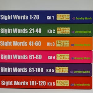 May include: A stack of six colorful boxes for sight word learning. Each box is a different color, including blue, green, orange, pink, purple, and red. The boxes have white text that reads "Sight Words" followed by a range of numbers, and "12 games in 1 box."