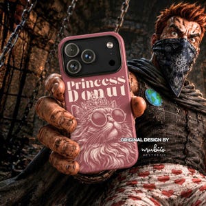 May include: A dusty pink smartphone case featuring the white text Princess Donut above a detailed line art illustration of a cat wearing a crown and round sunglasses. The case has a black camera module cutout with three circular lens openings.