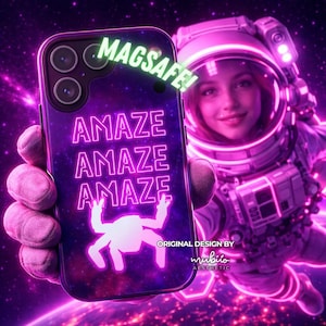 May include: A MagSafe phone case with a purple space-themed design. The case features the word "AMAZE" repeated three times in neon pink, along with a white crab silhouette. The word "MAGSAFE!" is in green. The design is by "mubio aesthetic".