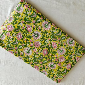 Może przedstawiać: Złożona tkanina z żywym wzorem kwiatowym. Wzór przedstawia różowe i białe kwiaty z zielonymi liśćmi i łodygami na żółtym tle. Tkanina jest prawdopodobnie bawełniana lub podobna.