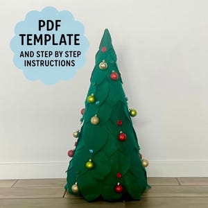 May include: A green felt Christmas tree decorated with colorful ornaments. The tree has a cone shape and is adorned with red, gold, and green baubles. Text on the left says "PDF TEMPLATE AND STEP BY STEP INSTRUCTIONS".