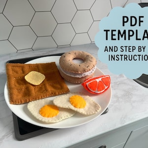 May include: A felt breakfast set on a white plate includes toast with butter, a bagel, a grapefruit slice, and two fried eggs. The image also includes the text "PDF TEMPLATE AND STEP BY STEP INSTRUCTIONS".