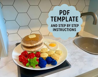 May include: A felt breakfast set on a white plate, including pancakes, an egg, strawberries, blueberries, and butter. The plate sits on a black surface. Text on a blue cloud shape reads "PDF TEMPLATE AND STEP BY STEP INSTRUCTIONS."