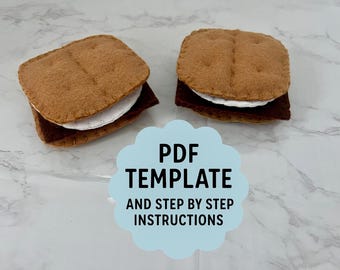 May include: Two felt s'mores, each with a brown graham cracker top and bottom, a white marshmallow, and a dark chocolate layer. The image includes a light blue cloud-shaped graphic with the text "PDF TEMPLATE AND STEP BY STEP INSTRUCTIONS."