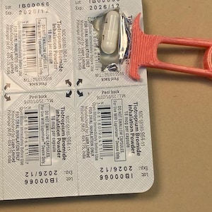 May include: A blister pack of Tiotropium Bromide inhalation powder capsules, 18 mcg per capsule. The expiration date is 2026/12. A red plastic device is partially visible. The capsules are for oral inhalation only.